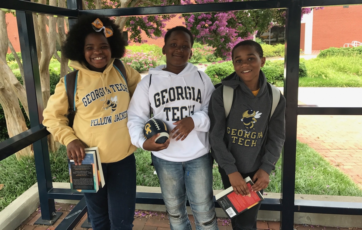 School and Community Engagement - three students pose in Georgia Tech sweatshirts