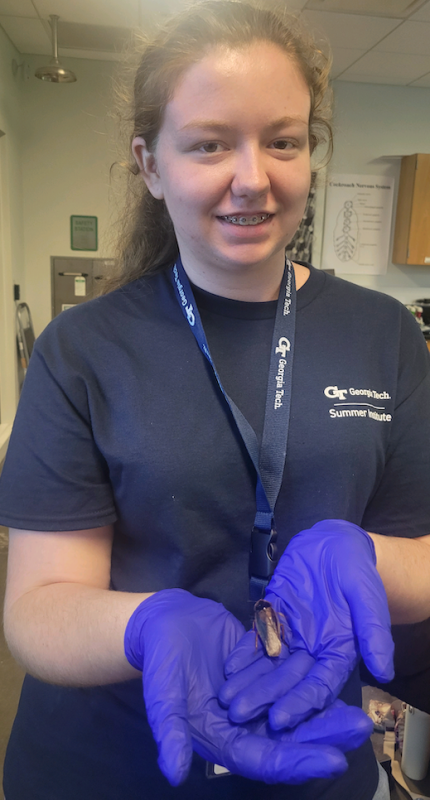 Image of Kelseigh Williams holding a roach in a science lab.