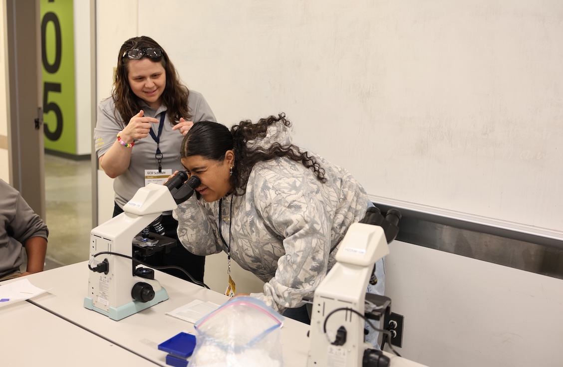 Image of student looking through microscope at the gostem college and stem fair.